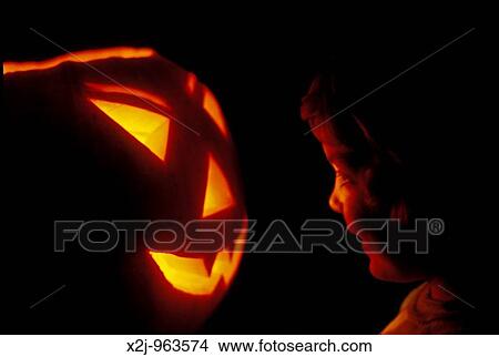 Detroit, Michigan - Mariel West, 4, inspects a pumpkin carved into a jack-? o-lantern for haloween MR View Large Photo Image Picture - Detroit, Michigan - Mariel West, 4, inspects a pumpkin carved into a jack-? o-lantern for haloween MR. Fotosearch