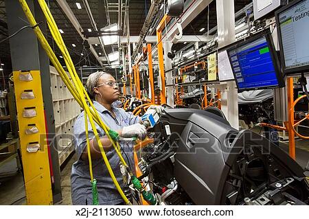 Stock Image - Detroit, Michigan - Members of the United Auto Workers union build dashboards for Ford vehicles at Detroit Manufacturing Systems. This worker is performing tests on nearly-completed assemblies.. Fotosearch