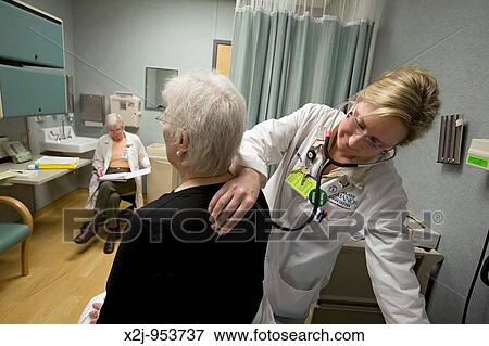 Detroit, Michigan - Nurse practitioner Sarah Jacob listens to Pat Lancaster's lungs with a stethoscope, as research nurse Susan Newell reviews her notes View Large Photo Image Stock Photo - Detroit, Michigan - Nurse practitioner Sarah Jacob listens to Pat Lancaster's lungs with a stethoscope, as research nurse Susan Newell reviews her notes. Fotosearch