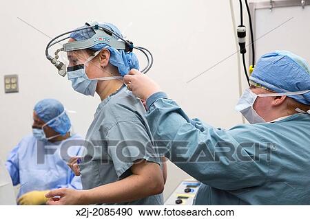 Stock Image - Detroit, Michigan - Registered nurse Tammy Brown (right) adjust a light that Dr. Stephanie Munns will wear during surgery at Karmanos Cancer Institute.. Fotosearch