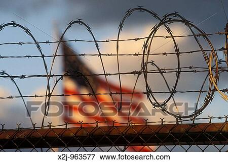 Detroit, Michigan - The American flag flies over a warehouse protected with razor wire View Large Photo Image Stock Photo - Detroit, Michigan - The American flag flies over a warehouse protected with razor wire. Fotosearch