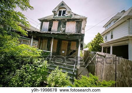 Stock Photo - Dilapidated home in the Flatlands neighborhood of Brooklyn in New York. After being damaged by squatters and a fire the city is deciding whether to tear down the house, but only after numerous complaints from neighbors over the condition of the building.. Fotosearch