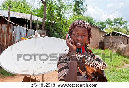 Dimeka Ethiopia Africa village Lower Omo Valley portrait of young Hamar girl with cell phone communicating and satellite dish in back 17 View Large Photo Image Stock Photo - Dimeka Ethiopia Africa village Lower Omo Valley portrait of young Hamar girl with cell phone communicating and satellite dish in back 17. Fotosearch
