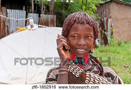 Dimeka Ethiopia Africa village Lower Omo Valley portrait of young Hamar girl with cell phone communicating and satellite dish in back 17 View Large Photo Image Stock Photograph - Dimeka Ethiopia Africa village Lower Omo Valley portrait of young Hamar girl with cell phone communicating and satellite dish in back 17. Fotosearch