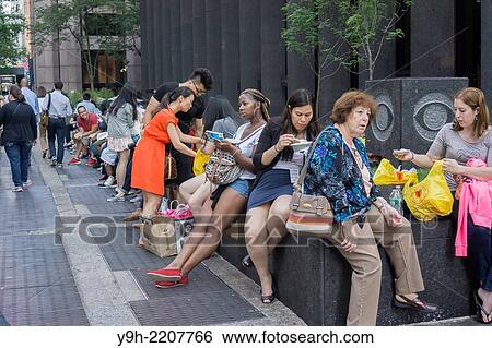Stock Photograph - Diners in front of the popular Halal Guys food cart on Sixth Avenue and West 53rd Street in New York.. Fotosearch