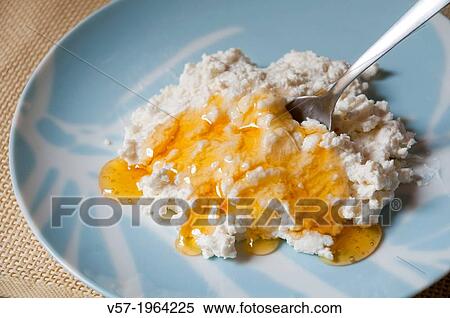 Stock Photography - Dipping spoon in curd cheese with honey.. Fotosearch