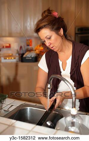 Dishwashing - Woman cleaning dishes after cooking in her kitchen View Large Photo Image Stock Image - Dishwashing - Woman cleaning dishes after cooking in her kitchen. Fotosearch