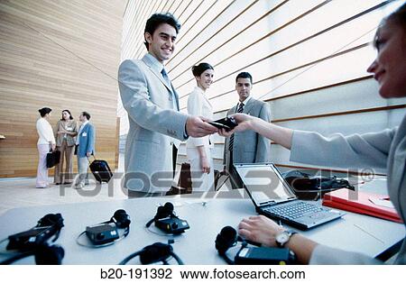 Stock Image - Distribution of simultaneous translation devices at business trade show. Fotosearch