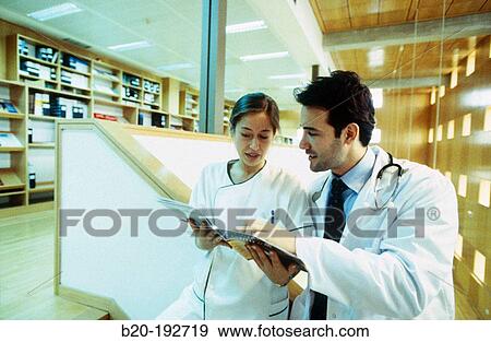 Doctor and nurse consulting medical magazine View Large Photo Image Stock Photo - Doctor and nurse consulting medical magazine. Fotosearch