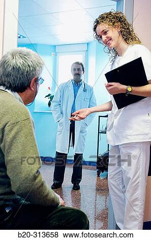 Stock Photo - Doctor and nurse with patient in doctor's office of hospital. Fotosearch