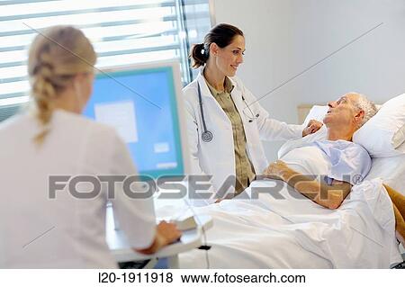 Stock Photo - doctor attending to patient in hospital room, Onkologikoa Hospital, Oncology Institute, Case Center for prevention, diagnosis and treatment of cancer, Donostia, San Sebastian, Gipuzkoa, Basque Country, Spain. Fotosearch