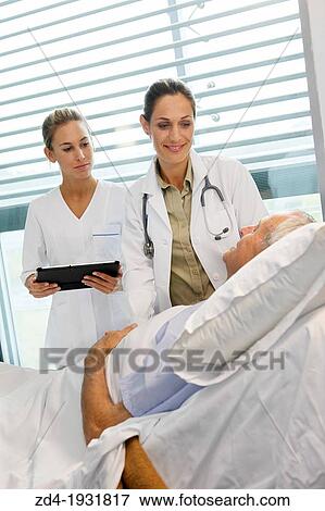 Stock Photo - doctor attending to patient in hospital room, Onkologikoa Hospital, Oncology Institute, Case Center for prevention, diagnosis and treatment of cancer, Donostia, San Sebastian, Gipuzkoa, Basque Country, Spain. Fotosearch
