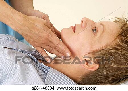 Picture - Doctor auscultating patient's throat and neck. Fotosearch