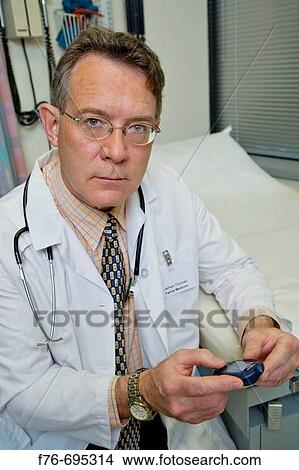 Doctor holding blood glucose meter View Large Photo Image Picture - Doctor holding blood glucose meter. Fotosearch