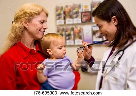Doctor / pediatrician examines baby girl being held by her mother in medical office during physical exam View Large Photo Image Stock Image - Doctor / pediatrician examines baby girl being held by her mother in medical office during physical exam. Fotosearch