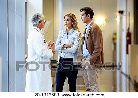 Stock Image - Doctor talking with the patient's family in the hospital corridor, Onkologikoa Hospital, Oncology Institute, Case Center for prevention, diagnosis and treatment of cancer, Donostia, San Sebastian, Gipuzkoa, Basque Country, Spain. Fotosearch