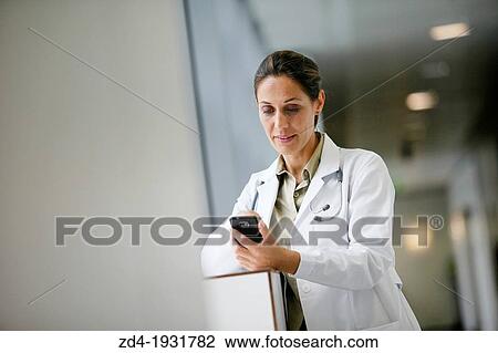 Stock Image - Doctor with smartphone in corridor, Onkologikoa Hospital, Oncology Institute, Case Center for prevention, diagnosis and treatment of cancer, Donostia, San Sebastian, Gipuzkoa, Basque Country, Spain. Fotosearch