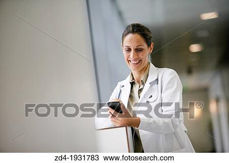 Stock Image - Doctor with smartphone in corridor, Onkologikoa Hospital, Oncology Institute, Case Center for prevention, diagnosis and treatment of cancer, Donostia, San Sebastian, Gipuzkoa, Basque Country, Spain. Fotosearch