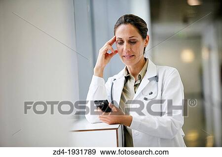 Stock Photo - Doctor with smartphone in corridor, Onkologikoa Hospital, Oncology Institute, Case Center for prevention, diagnosis and treatment of cancer, Donostia, San Sebastian, Gipuzkoa, Basque Country, Spain. Fotosearch
