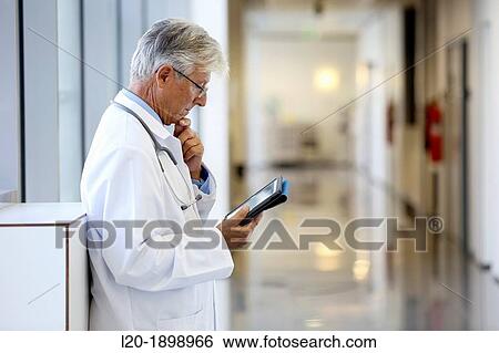 Stock Photograph - Doctor with tablet in corridor, Onkologikoa Hospital, Oncology Institute, Case Center for prevention, diagnosis and treatment of cancer, Donostia, San Sebastian, Gipuzkoa, Basque Country, Spain. Fotosearch