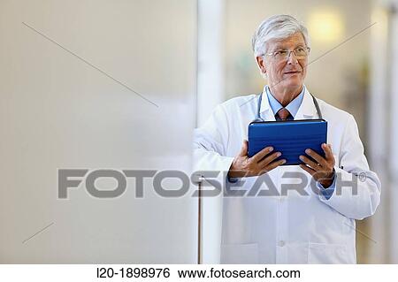 Stock Photograph - Doctor with tablet in corridor, Onkologikoa Hospital, Oncology Institute, Case Center for prevention, diagnosis and treatment of cancer, Donostia, San Sebastian, Gipuzkoa, Basque Country, Spain. Fotosearch