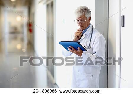 Stock Photograph - Doctor with tablet in corridor, Onkologikoa Hospital, Oncology Institute, Case Center for prevention, diagnosis and treatment of cancer, Donostia, San Sebastian, Gipuzkoa, Basque Country, Spain. Fotosearch