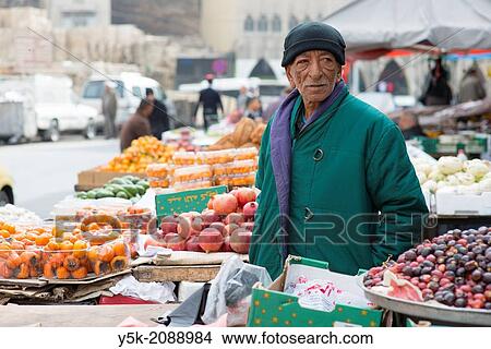 Picture - Down Town, Amman, Jordan, Middle-East. Seventy (70) year old owner of a market stall, down town Amman, where he sells regionally produced fruits and vegetables. In a previous life, he worked in the Rotterdam harbor, returning home after his retirement.. Fotosearch