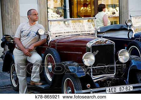 Stock Image - Drivers standing by old Skoda car used for sightseeing, Prague, Czech Republic. Fotosearch