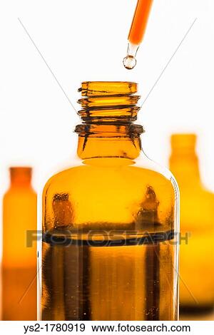 Dropper with red substance held over transparent brown bottle View Large Photo Image Stock Photo - Dropper with red substance held over transparent brown bottle. Fotosearch