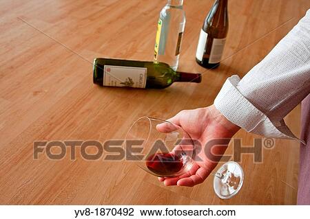 Stock Image - Drunken male holding a glass of red wine. Fotosearch