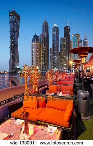 Stock Image - Dubai Marina by night, restaurant on the promenade in Marina district, Dubai, United Arab Emirates. Fotosearch