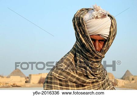 Stock Photograph - During the winter, a muslim man belonging to the Sindhi community is protecting himself against the cold. Thar desert, India.. Fotosearch
