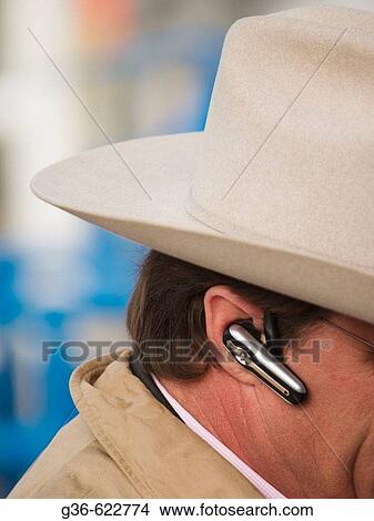 Picture - Earpiece and cowboy hat contrast on a man in Tucson, Arizona. Fotosearch