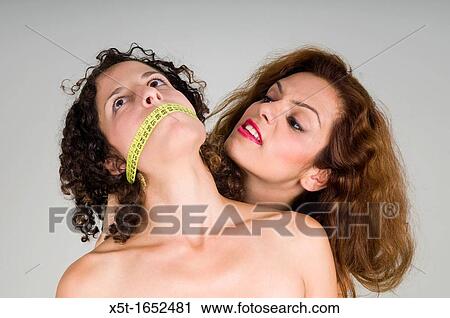 Stock Image - Eating disorder - a woman's mouth is gagged with a tape measure implying the affect of body image on Anorexia and other eating disorders. Fotosearch