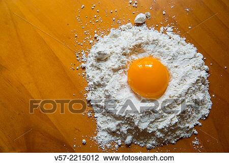 Stock Image - Egg yolk on flour.. Fotosearch