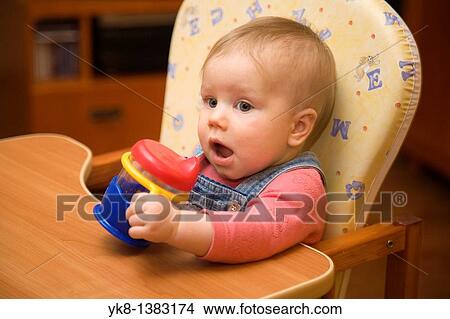 Picture - Eight Month Old Infant Girl with Cup in High Chair. Fotosearch