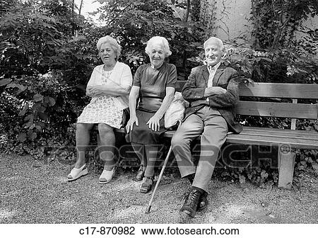 Eighties, black and white photo, people, elder people, two older women and one older man sitting on a bench, dress, waistcoat, jacket, trousers, aged 70 to 80 years View Large Photo Image Stock Image - Eighties, black and white photo, people, elder people, two older women and one older man sitting on a bench, dress, waistcoat, jacket, trousers, aged 70 to 80 years. Fotosearch