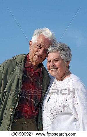 Elderly caucasian couple looking happy and laughing into the camera with bright blue sky in the background, Island of Amrum, Northfrisian, Schleswig_Holstein, Northern Germany, Europe View Large Photo Image Stock Photo - Elderly caucasian couple looking happy and laughing into the camera with bright blue sky in the background, Island of Amrum, Northfrisian, Schleswig_Holstein, Northern Germany, Europe. Fotosearch