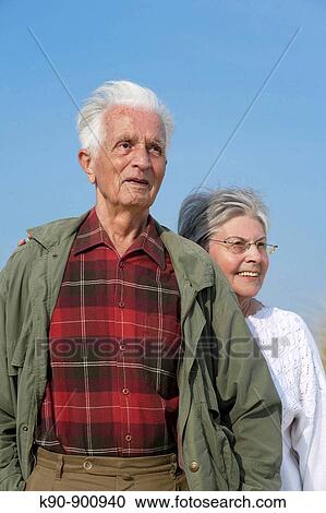 Elderly caucasian couple standing besides each other and looking into the far distance with bright blue sky in the background, Island of Amrum, Northfrisian, Schleswig-Holstein, Northern Germany, Europe View Large Photo Image Stock Image - Elderly caucasian couple standing besides each other and looking into the far distance with bright blue sky in the background, Island of Amrum, Northfrisian, Schleswig-Holstein, Northern Germany, Europe. Fotosearch
