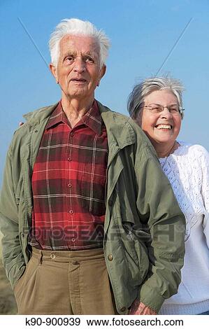 Elderly caucasian couple standing besides each other and looking into the far distance with bright blue sky in the background, Island of Amrum, Northfrisian, Schleswig_Holstein, Northern Germany, Europe View Large Photo Image Stock Photo - Elderly caucasian couple standing besides each other and looking into the far distance with bright blue sky in the background, Island of Amrum, Northfrisian, Schleswig_Holstein, Northern Germany, Europe. Fotosearch