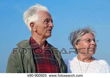 Stock Photography - Elderly caucasian couple standing besides each other and looking into the far distance with bright blue sky in the background, Island of Amrum, Northfrisian, Schleswig_Holstein, Northern Germany, Europe. Fotosearch