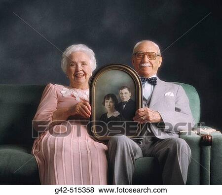Elderly couple holding photo from when they were just married. View Large Photo Image Stock Photo - Elderly couple holding photo from when they were just married.. Fotosearch