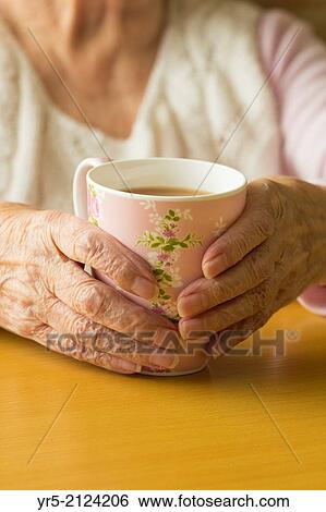 Elderly lady holding cup of tea. England, United Kingdom. View Large Photo Image Stock Photograph - Elderly lady holding cup of tea. England, United Kingdom.. Fotosearch