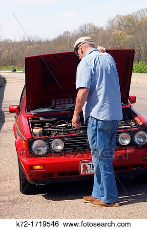 Stock Photograph - Elderly man checking under the hood for a roadside car problem. Fotosearch