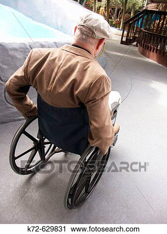 Stock Image - Elderly man in wheelchair enjoys being a tourist. Fotosearch
