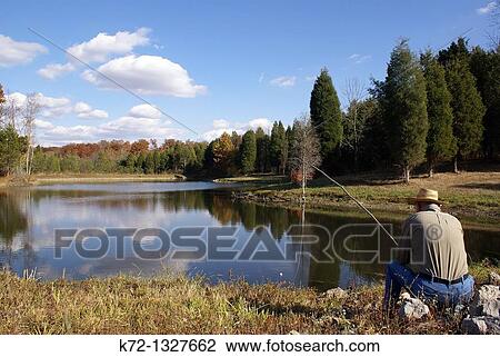 Elderly man sits on shore fishing with an old cane pole View Large Photo Image Stock Image - Elderly man sits on shore fishing with an old cane pole. Fotosearch