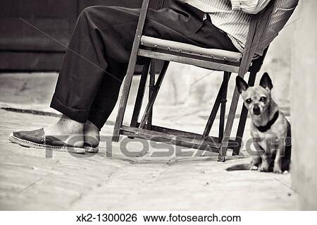 Elderly man sitting on typical Minorca chair (aka.? Coca Rossa? ) with dog. Ciutadella de Menorca, Minorca, Balearic Islands, Spain. View Large Photo Image Stock Photograph - Elderly man sitting on typical Minorca chair (aka.? Coca Rossa? ) with dog. Ciutadella de Menorca, Minorca, Balearic Islands, Spain.. Fotosearch