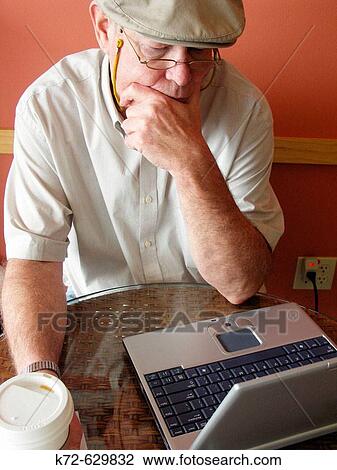 Elderly man thinking about display on laptop screen while sitting in a coffee shop View Large Photo Image Stock Image - Elderly man thinking about display on laptop screen while sitting in a coffee shop. Fotosearch