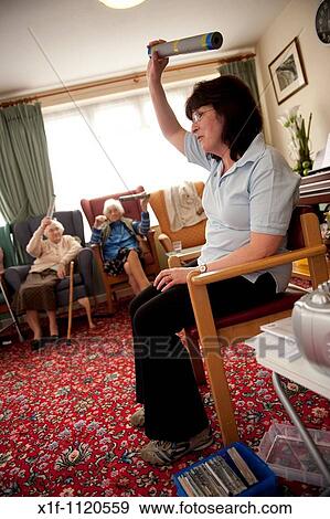 Elderly residents of a sheltered housing scheme doing light exercises while seated, UK View Large Photo Image Stock Photo - Elderly residents of a sheltered housing scheme doing light exercises while seated, UK. Fotosearch