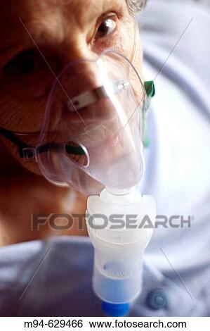 Stock Photograph - Elderly woman using an aerosol mask. Fotosearch
